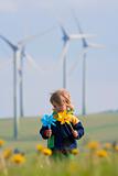 boy with long hair holding pinwheels standing in front of wind turbines