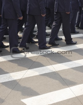 Marched soldiers at a pedestrian crossing of urban street 