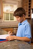 Boy doing homework at kitchen counter.