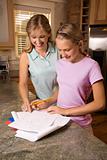 Mom helping daughter with homework at kitchen counter.