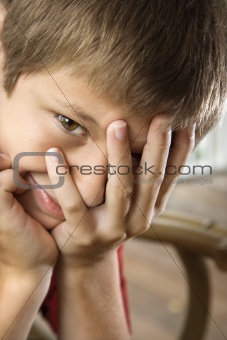 Boy with hand partially over face.
