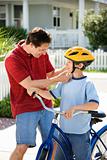 Dad helping son with bicycle helmet.