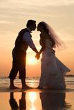 Bride and groom kissing on beach.