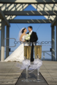 Champagne glasses with bride and groom in background.