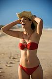 Woman in bikini holding hat.