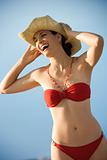 Woman in bikini holding hat.