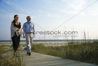 Couple holding hands on coastal walkway.