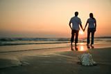 Couple holding hands on beach.