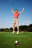 Woman jumping for joy over good golf shot.