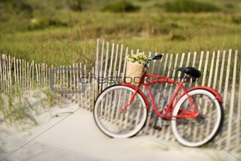 Bike leaning against fence at beach.
