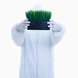 Man in biohazard suit holding pot of grass.