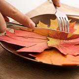 Hands carving meal of multicolored leaves.