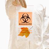 Man in biohazard suit holding biohazard bag.