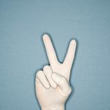 Hand wearing rubber glove making peace gesture.