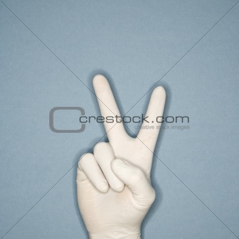 Hand wearing rubber glove making peace gesture.