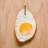 Fried egg nailed to wood. 