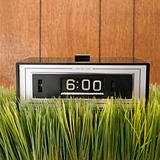 Retro alarm clock with wood paneling in background.