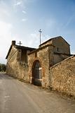 Stone building with gated archway in Tuscany.
