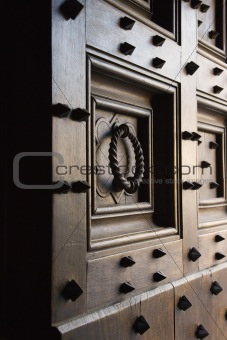 Wooden door with metal spikes and knocker.