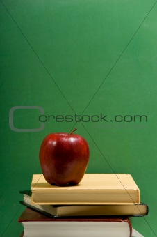 red apple on school books with green background