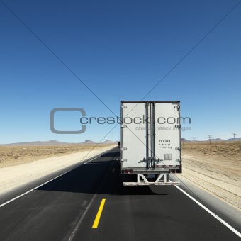 Truck traveling down highway towards horizon.