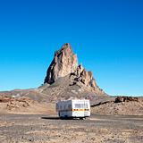 RV travelling toward rock formation in Monument Valley, Utah.