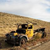 Old yellow pickup abandoned on hill. 