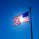 Waving American flag backlit by sun.