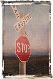 Railroad crossing and stop signs beside tracks.
