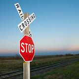 Railroad crossing and stop signs beside tracks.