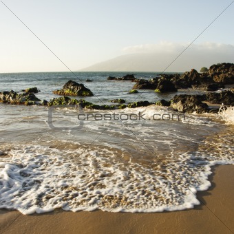 Landscape of waves lapping on rocky beach.