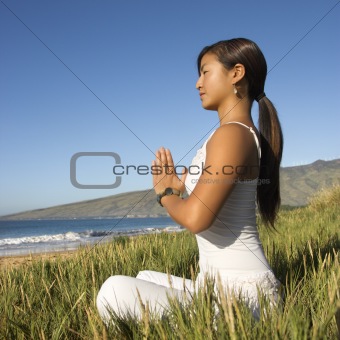 Woman sitting on with hands pressed together.