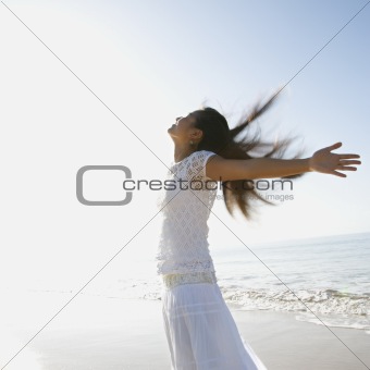 Woman at beach throwing her arms back behind her.