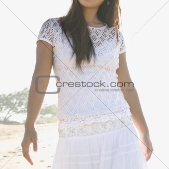 Woman at beach with hands by her hips.
