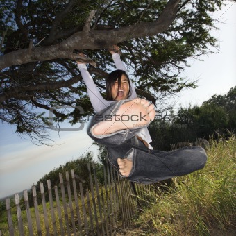 Womanholding on to a tree and kicking towards viewer.
