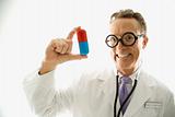 Doctor wearing eyeglasses holding an oversized pill.