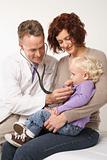 Mother holding her daughter while doctor uses stethoscope.