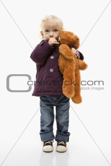 Female toddler sucking her thumb and holding  teddy bear.