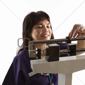 Nurse reading weight on scale.