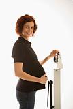 Pregnant woman standing on scale smiling.