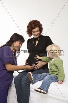Nurse holding stethoscope on pregnant woman's belly.