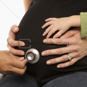 Nurse holding stethoscope on pregnant belly.