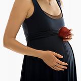 Pregnant woman holding apple.
