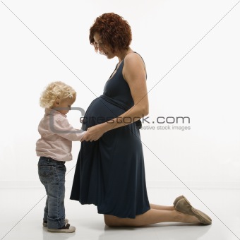 Child touching pregnant mom\'s belly.