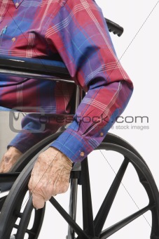 Hands gripping wheels of wheelchair.