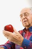 Elderly man holding apple.