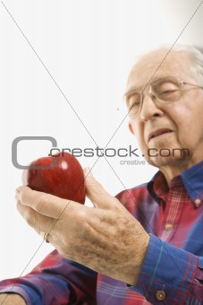 Elderly man holding apple.