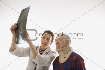 Doctor showing x-ray to elderly man in neck brace.