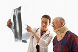 Doctor ponting at x-ray with elderly man in neck brace looking o