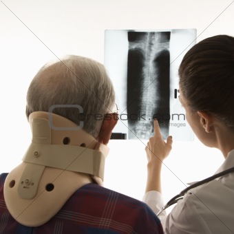 Over the shoulders view of doctor pointing at an x-ray as elderl